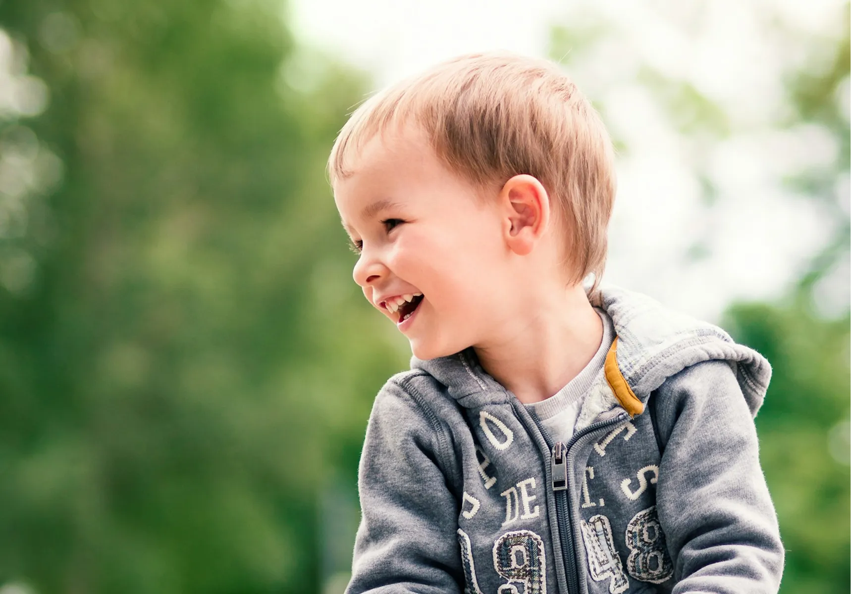 A young boy laughing outdoors